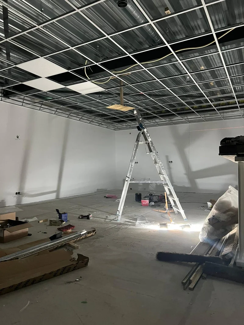 Systeemplafond in montage — metalen draagprofielen en plafondtegels, kantoor Amsterdam